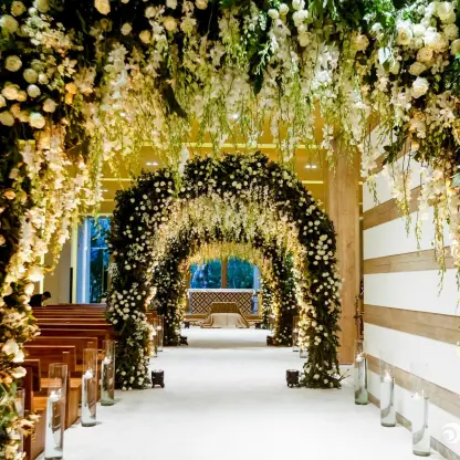 Indoor chapel wedding ceremony aisle with white floral arches at Grand Velas Riviera Maya