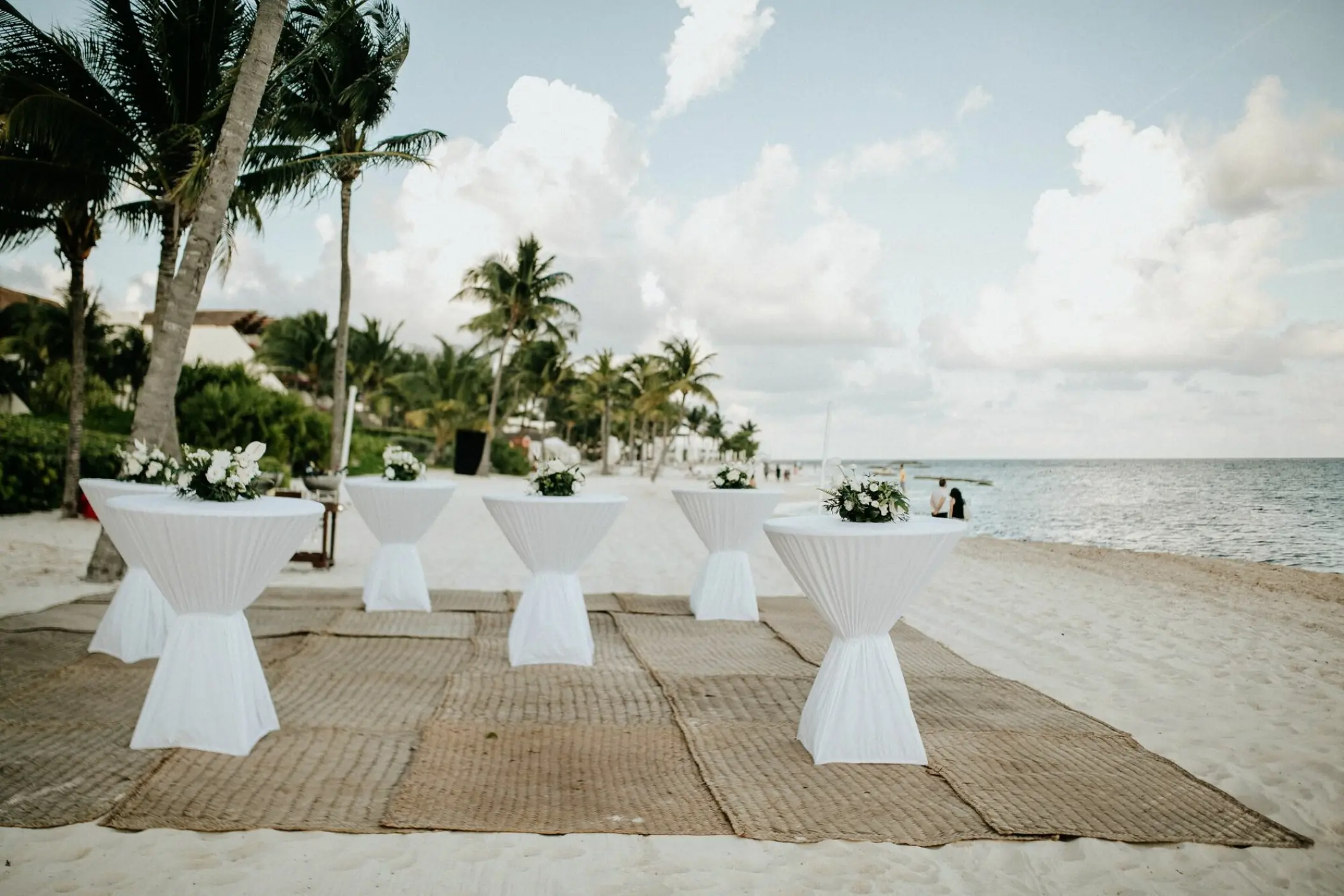 Cocktail reception setup with white high-top tables on the beach at Grand Velas Riviera Maya
