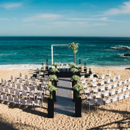 Beachfront wedding ceremony with white chairs and floral pillars at Grand Velas Los Cabos, Cabo San Lucas
