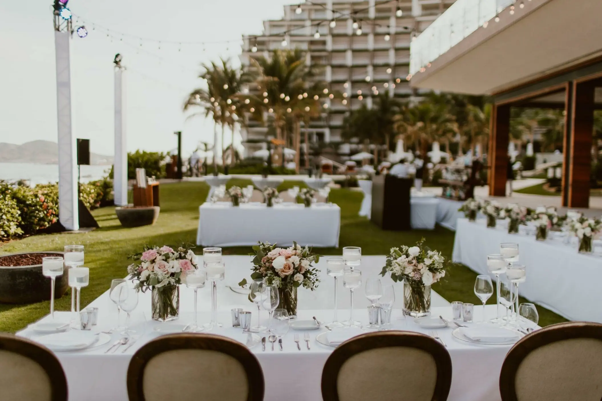 Outdoor wedding reception with floral centerpieces and string lights at Grand Velas Los Cabos, Cabo San Lucas