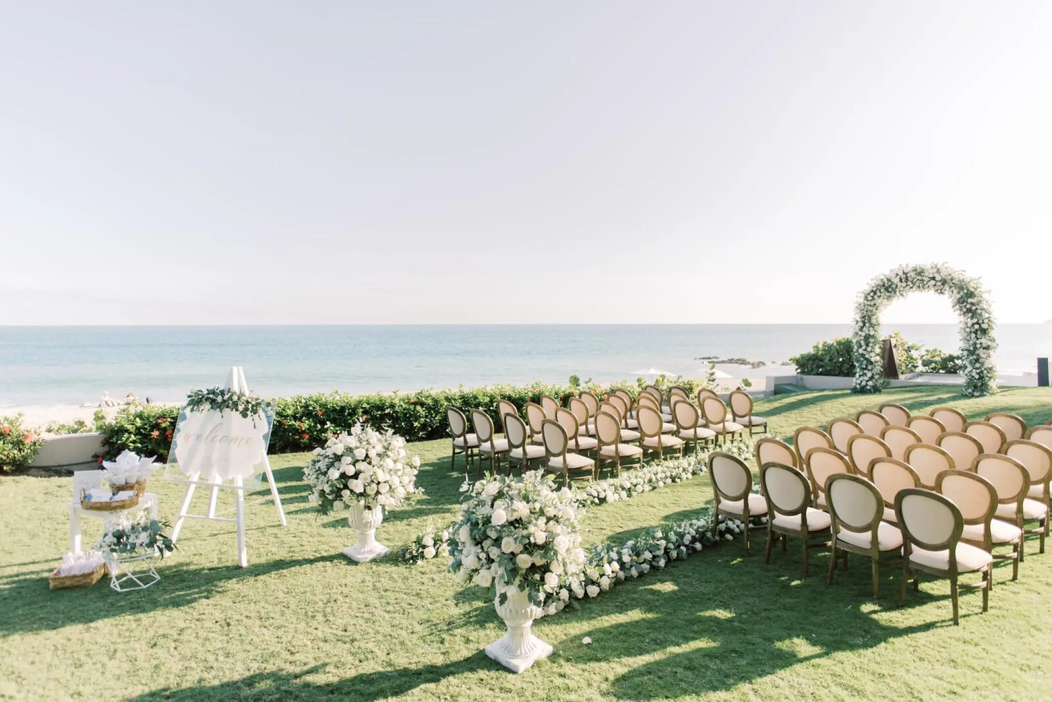 Garden wedding ceremony with white floral arch and ocean views at Grand Velas Los Cabos, Cabo San Lucas