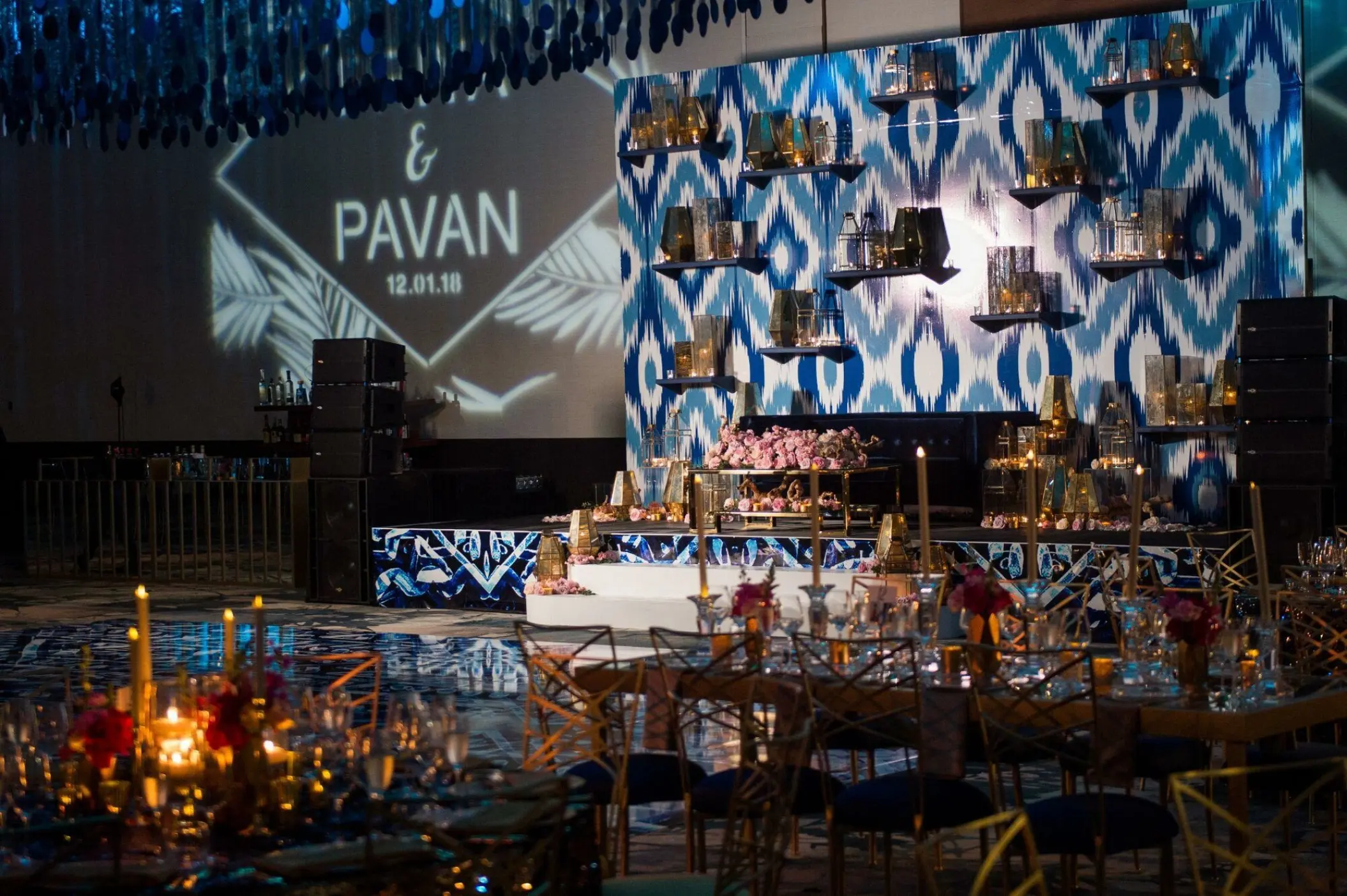 Grand Velas ballroom wedding reception with blue patterned backdrop and candlelight at Grand Velas Los Cabos