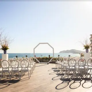 Oceanfront terrace wedding ceremony with white chairs and octagonal arch at Grand Velas Los Cabos, Cabo San Lucas