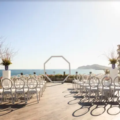 Oceanfront terrace wedding ceremony with white chairs and octagonal arch at Grand Velas Los Cabos, Cabo San Lucas