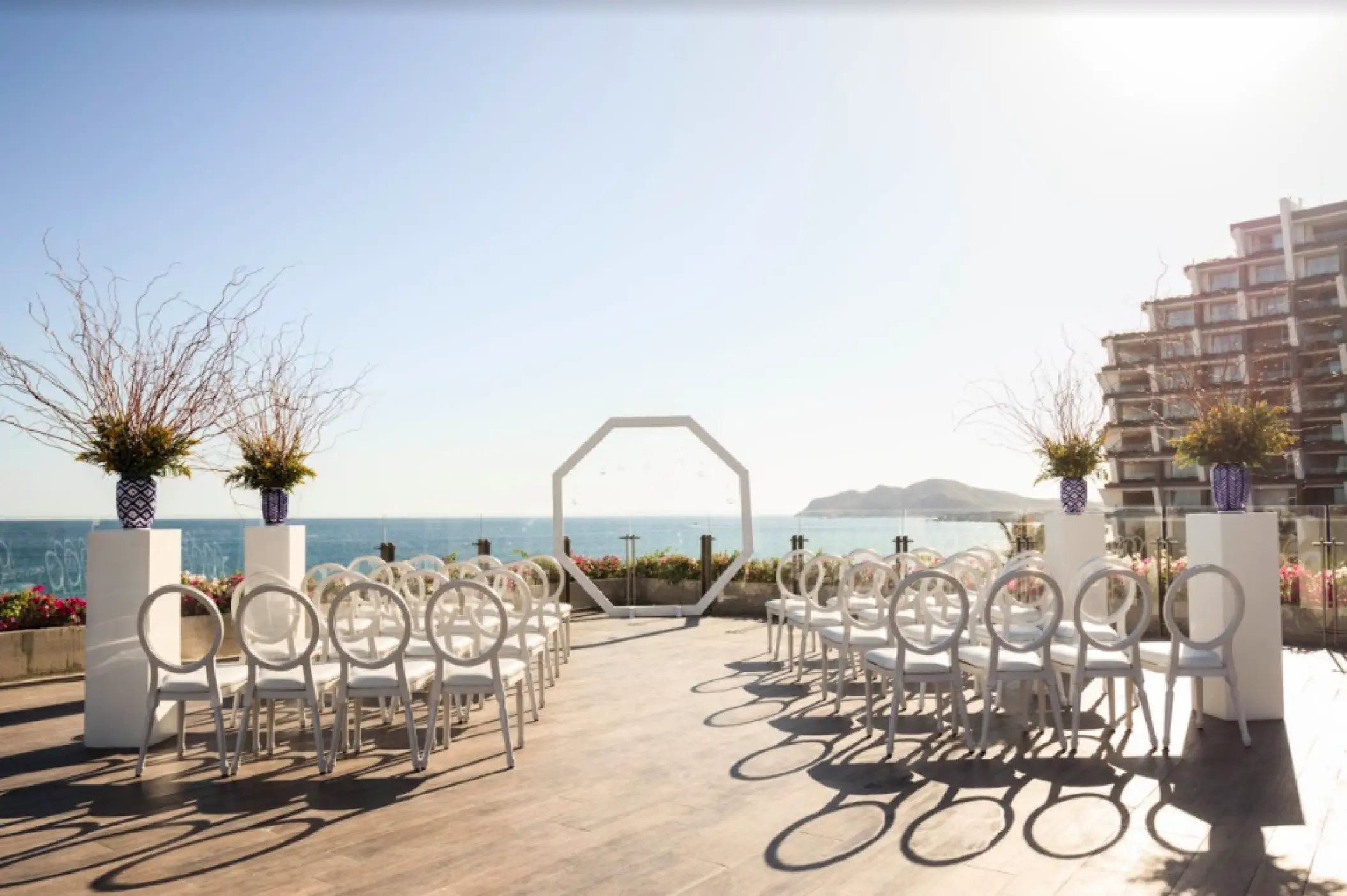 Oceanfront terrace wedding ceremony with white chairs and octagonal arch at Grand Velas Los Cabos, Cabo San Lucas