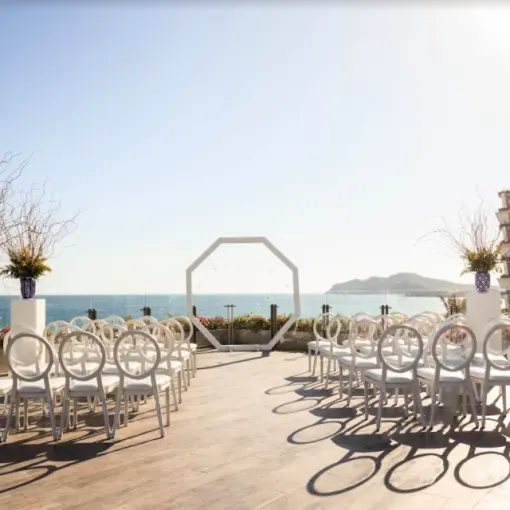 Oceanfront terrace wedding ceremony with white chairs and octagonal arch at Grand Velas Los Cabos, Cabo San Lucas