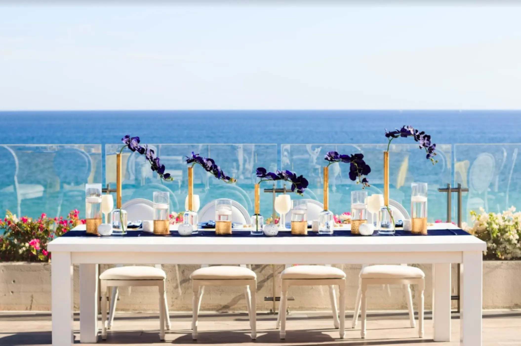 Terrace wedding reception at Grand Velas Los Cabos with white tables, purple florals, and ocean views, Cabo San Lucas