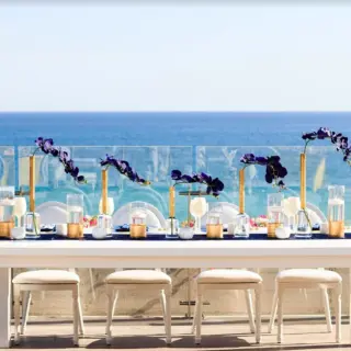 Terrace wedding reception at Grand Velas Los Cabos with white tables, purple florals, and ocean views, Cabo San Lucas