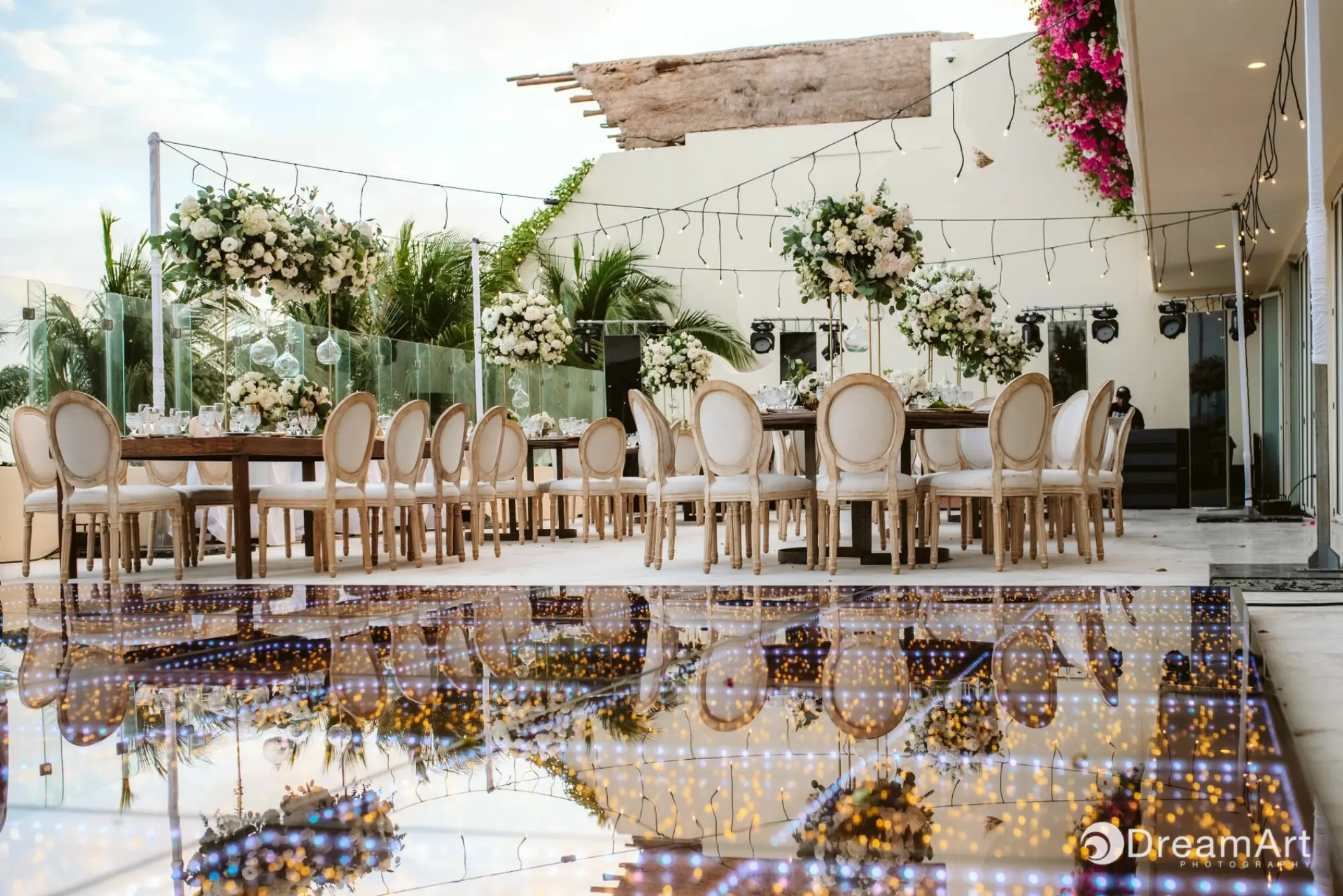 Terrace wedding reception with white floral centerpieces and string lights at Grand Velas Riviera Maya