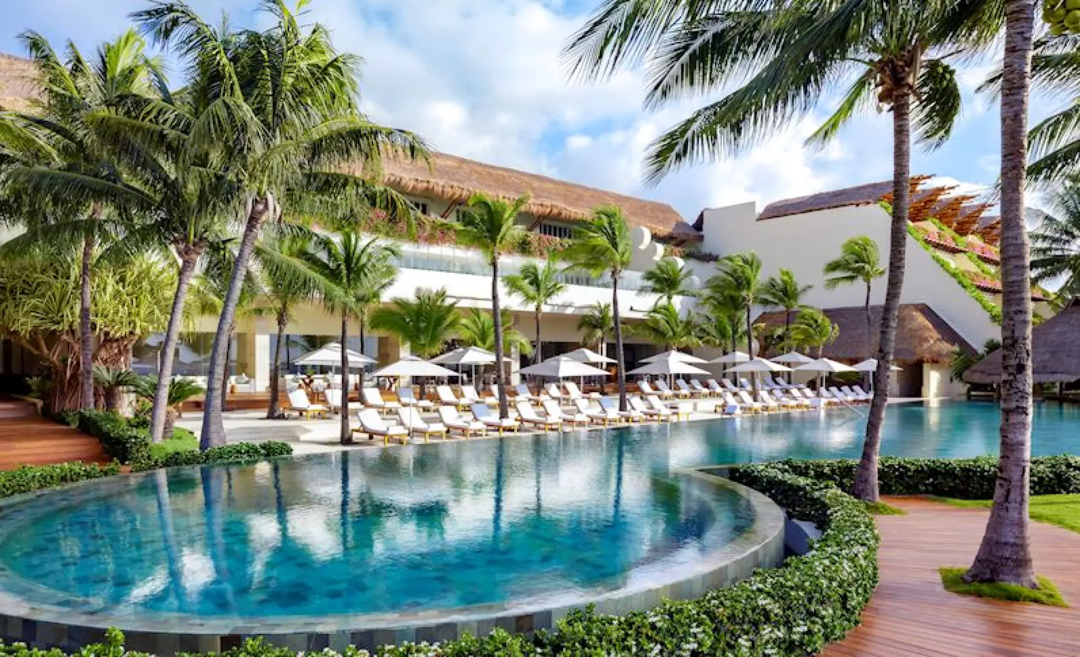Infinity pool and lounge area surrounded by palm trees at Grand Velas Riviera Maya, Riviera Maya