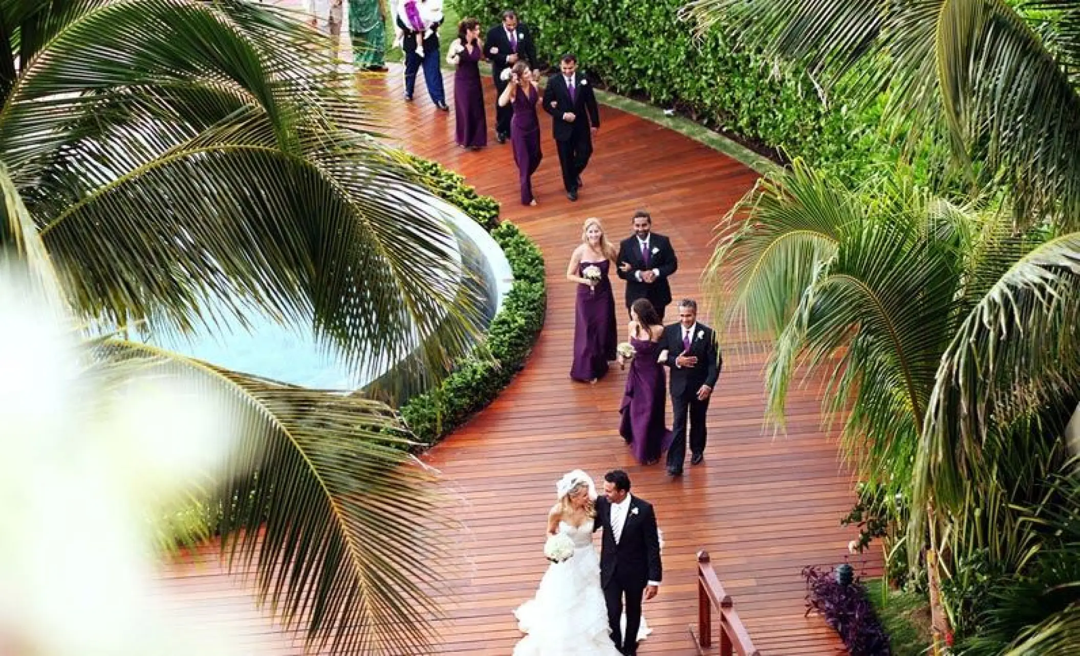 Bride and groom leading a wedding party along a garden path at Grand Velas Riviera Maya