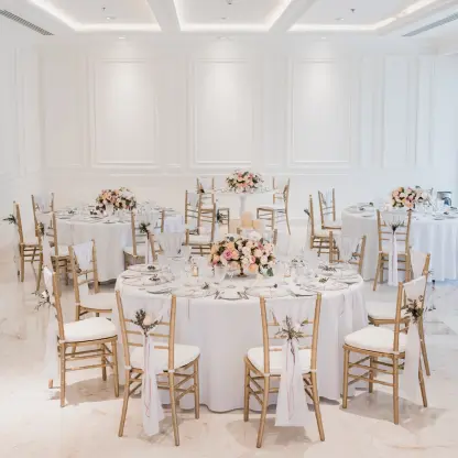 Indoor wedding reception at Grand Velas Riviera Maya with white table linens and gold Chiavari chairs