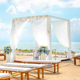 Beachfront wedding ceremony with white huppah and starfish at Grand Palladium Colonial, Riviera Maya