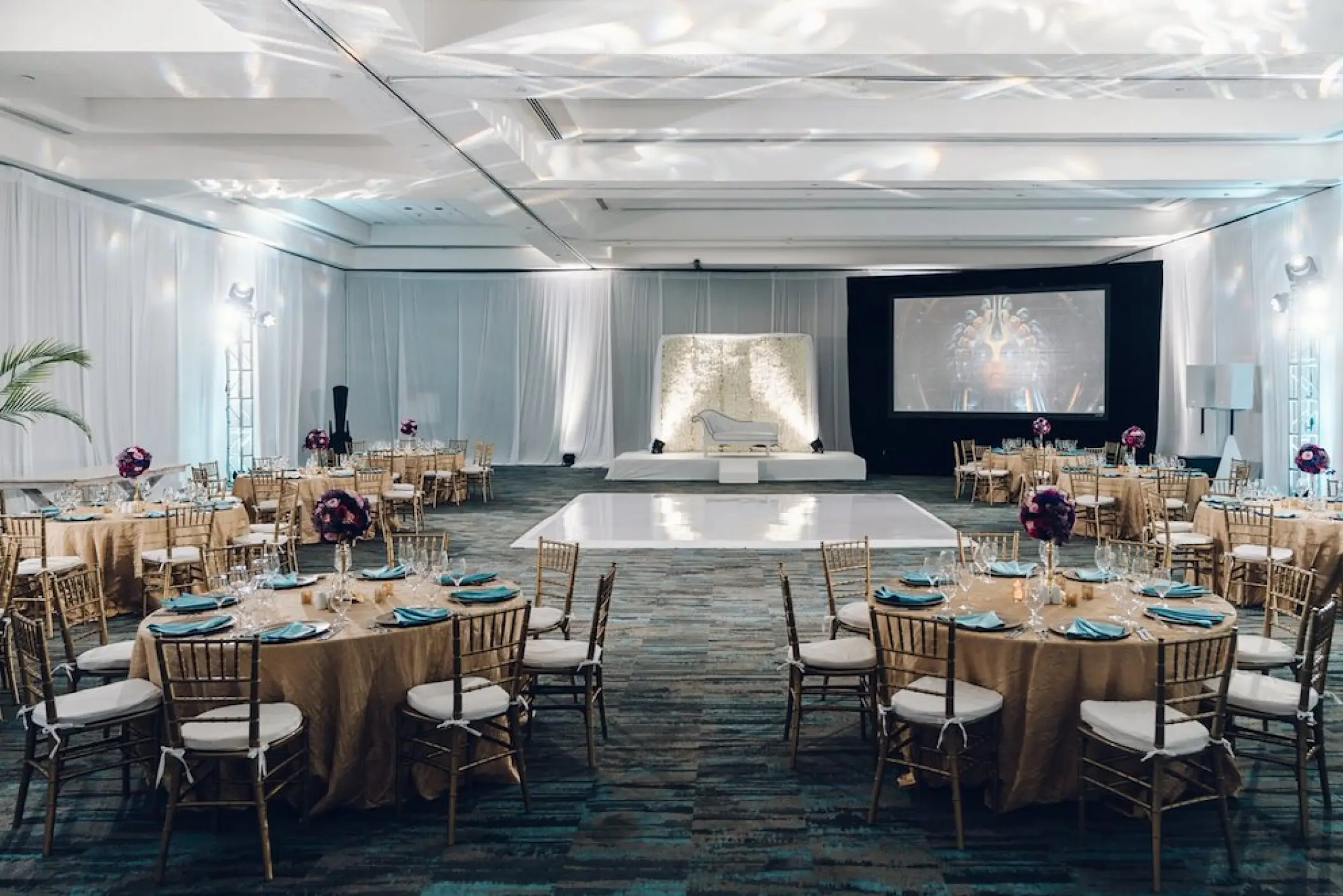 Indoor wedding reception at Hard Rock Riviera Maya with white dance floor and gold round tables