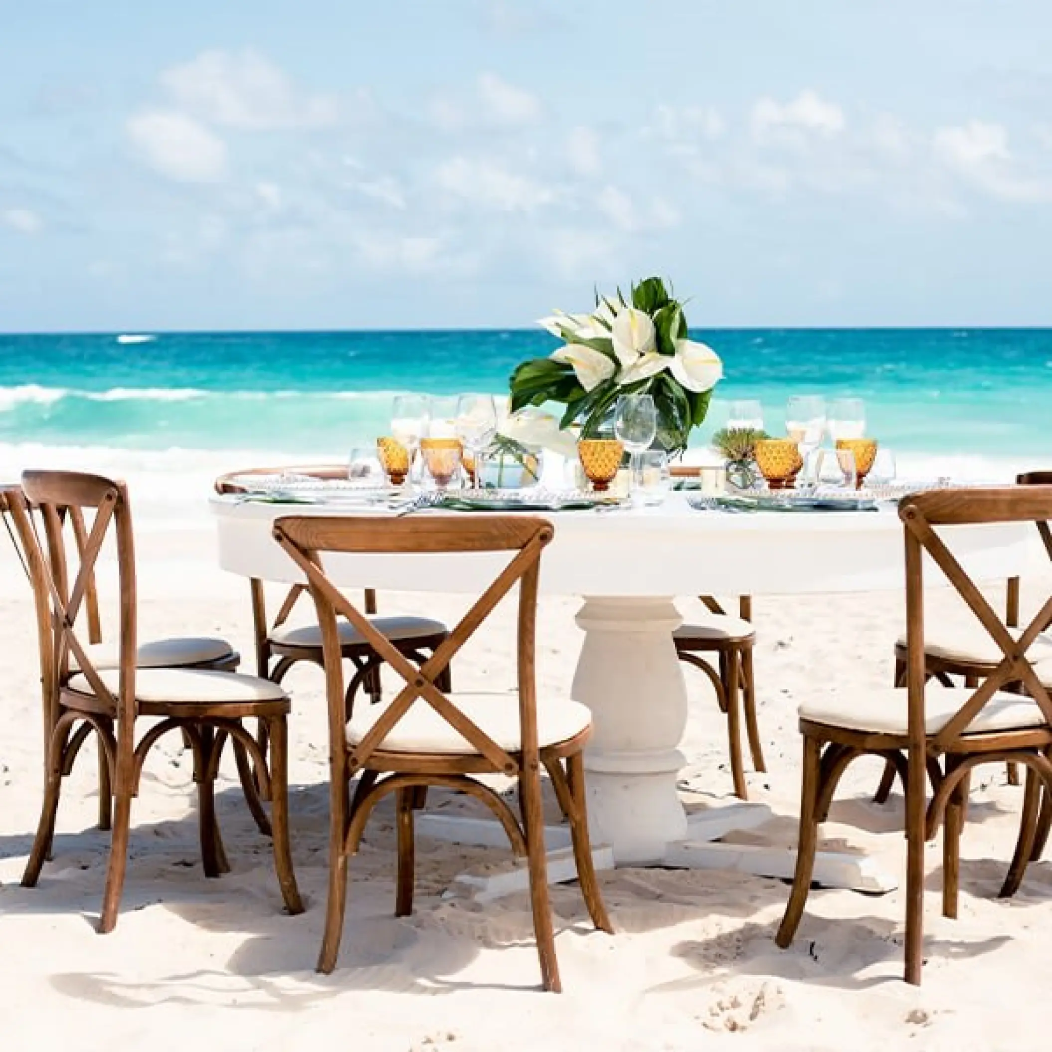 Beachfront wedding reception table with wooden cross-back chairs at Hard Rock Riviera Maya