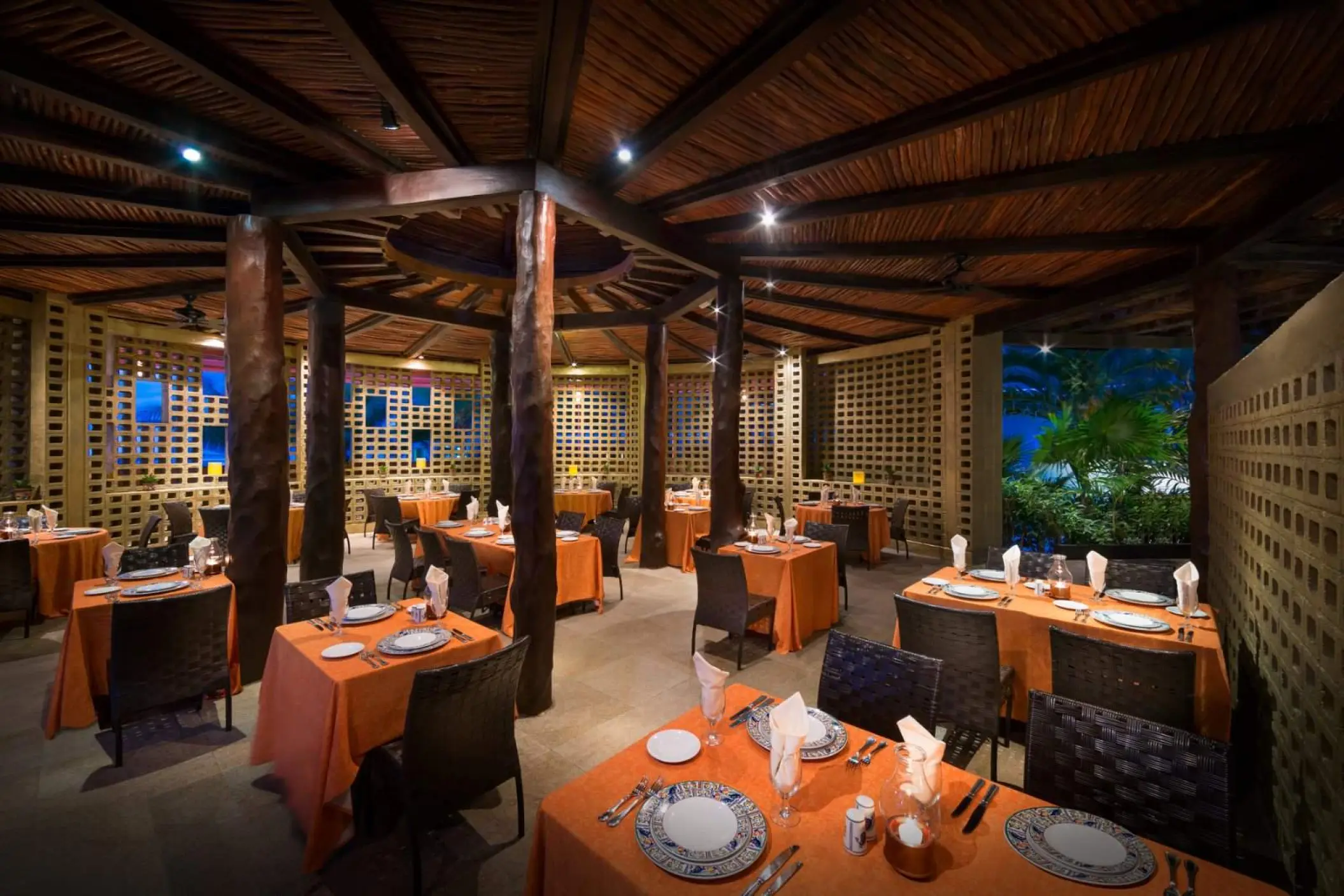 Frida restaurant interior with wood pillars and orange linens at Hard Rock Cancun