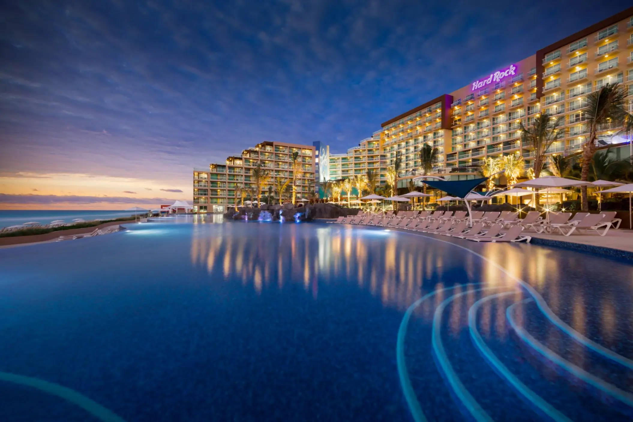 Main infinity pool and illuminated resort exterior at sunset, Hard Rock Cancun