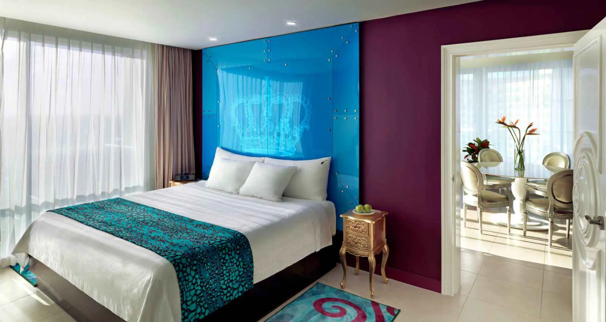Hard Rock Cancun guest suite with a blue glass headboard and separate dining area, Cancun