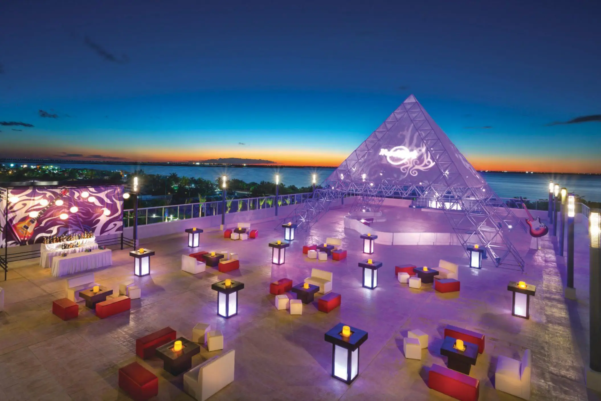Rooftop wedding reception with lit tables and a glass pyramid at Hard Rock Cancun