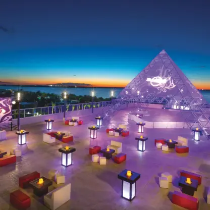 Rooftop wedding reception with lit tables and a glass pyramid at Hard Rock Cancun