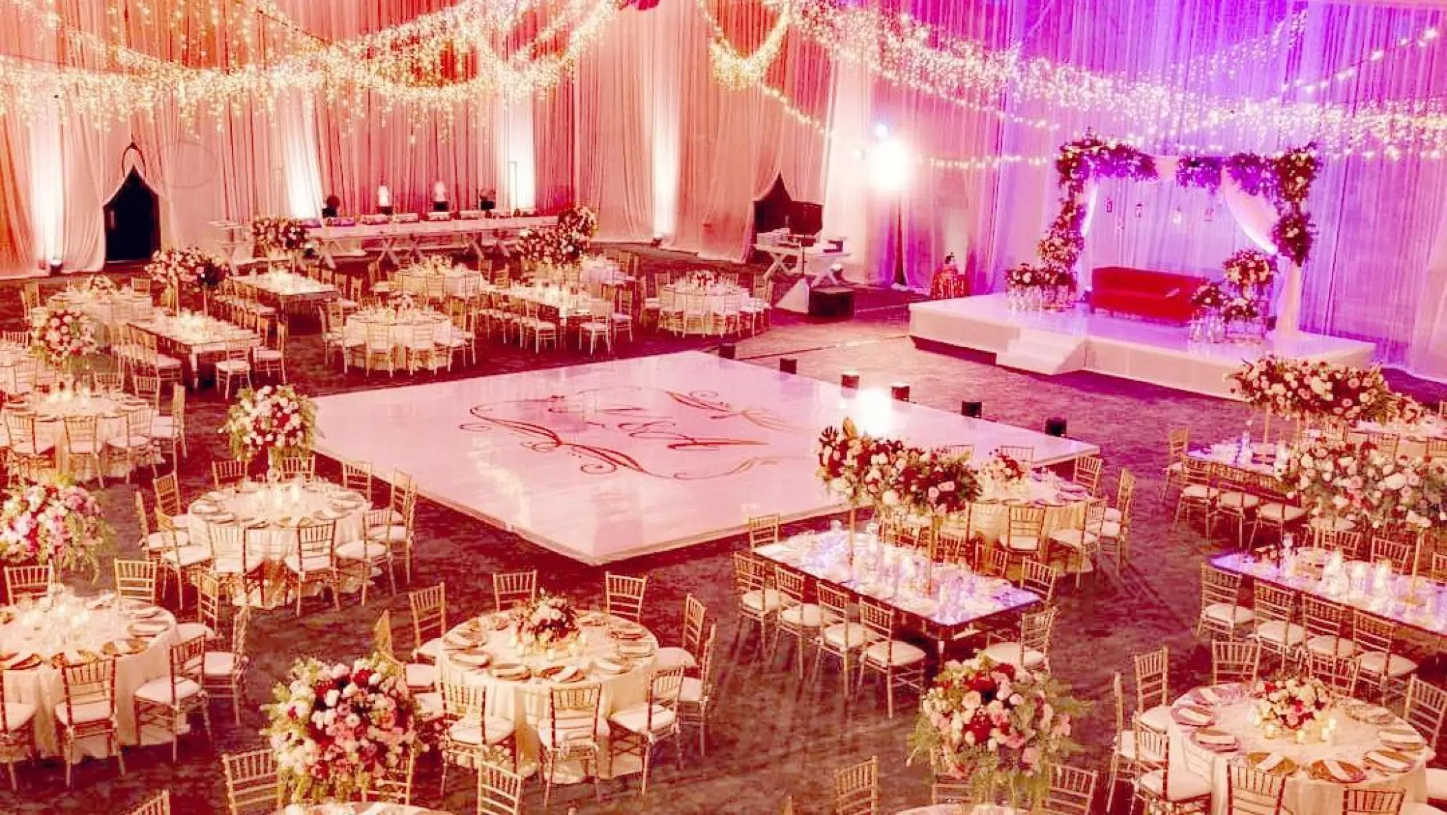 Indoor ballroom wedding reception at Hard Rock Cancun with white dance floor and floral centerpieces