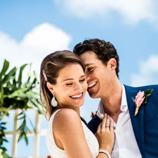 The bride and groom smiling under a blue sky at Hard Rock Cancun