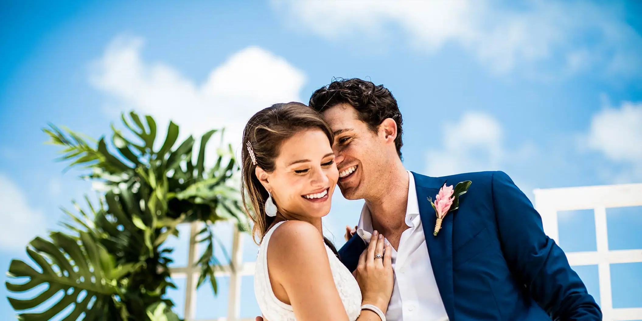 The bride and groom smiling under a blue sky at Hard Rock Cancun