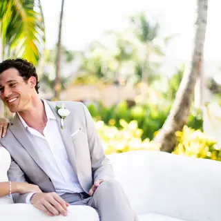 Bride and groom sitting on a white outdoor sofa at Hard Rock Cancun