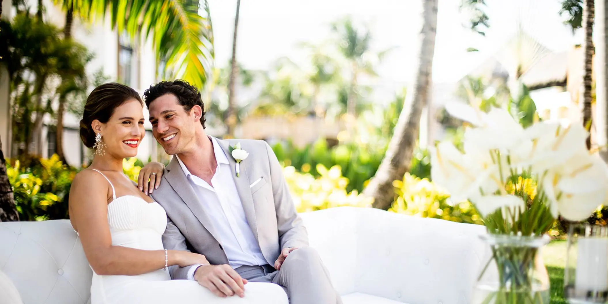 Bride and groom sitting on a white outdoor sofa at Hard Rock Cancun