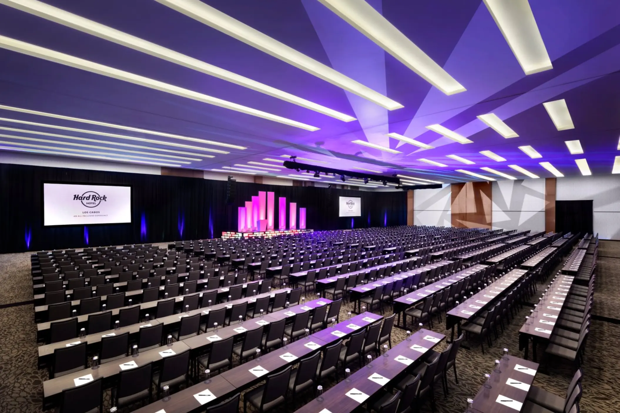 Large indoor Harmony ballroom with classroom setup and purple lighting at Hard Rock Los Cabos, Cabo San Lucas