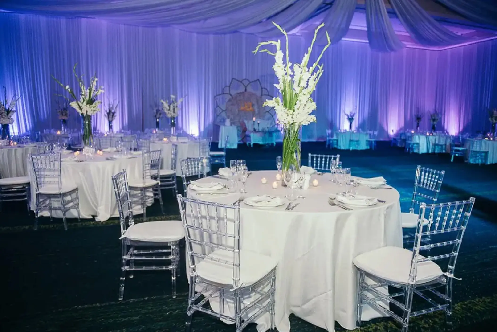 Ballroom wedding reception at Hard Rock Punta Cana featuring white linens and purple uplighting