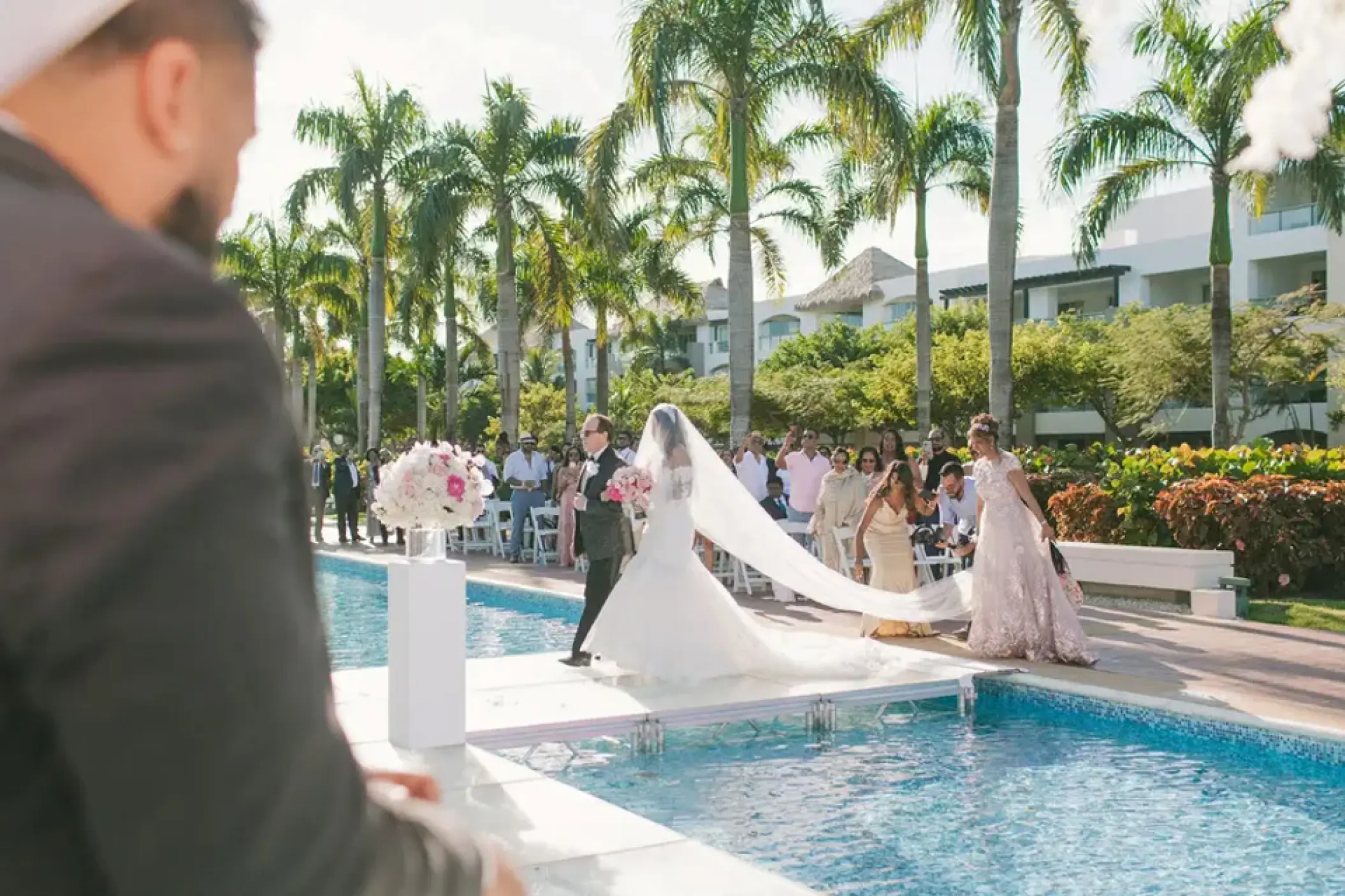 Bride walking down a poolside aisle during a wedding ceremony at Hard Rock Punta Cana