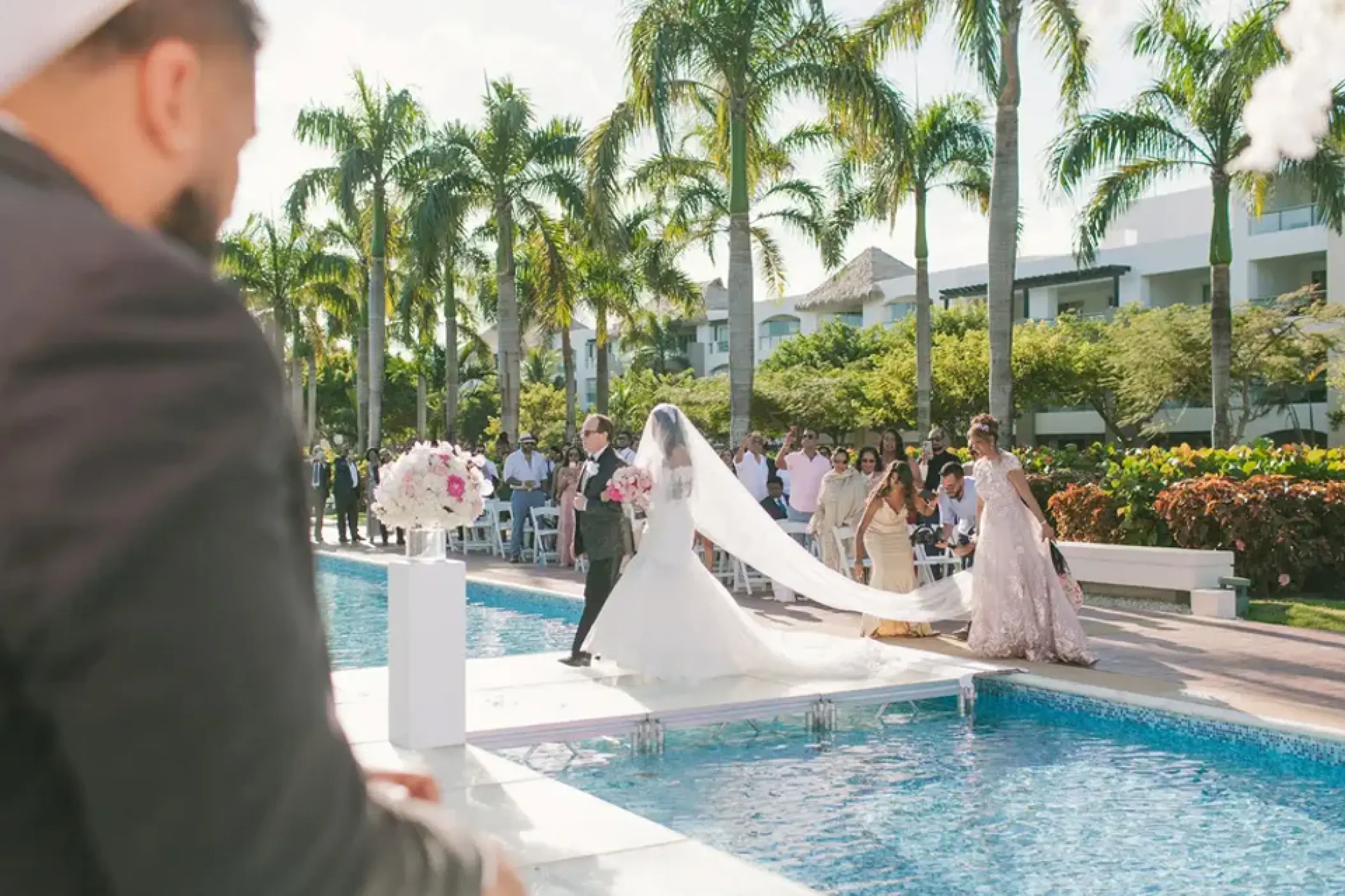Bride walking down a poolside aisle during a wedding ceremony at Hard Rock Punta Cana