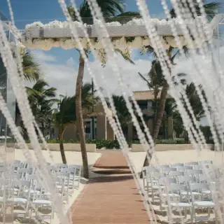 Beachfront wedding ceremony setup with crystal curtains and white floral arbor at Hard Rock Punta Cana
