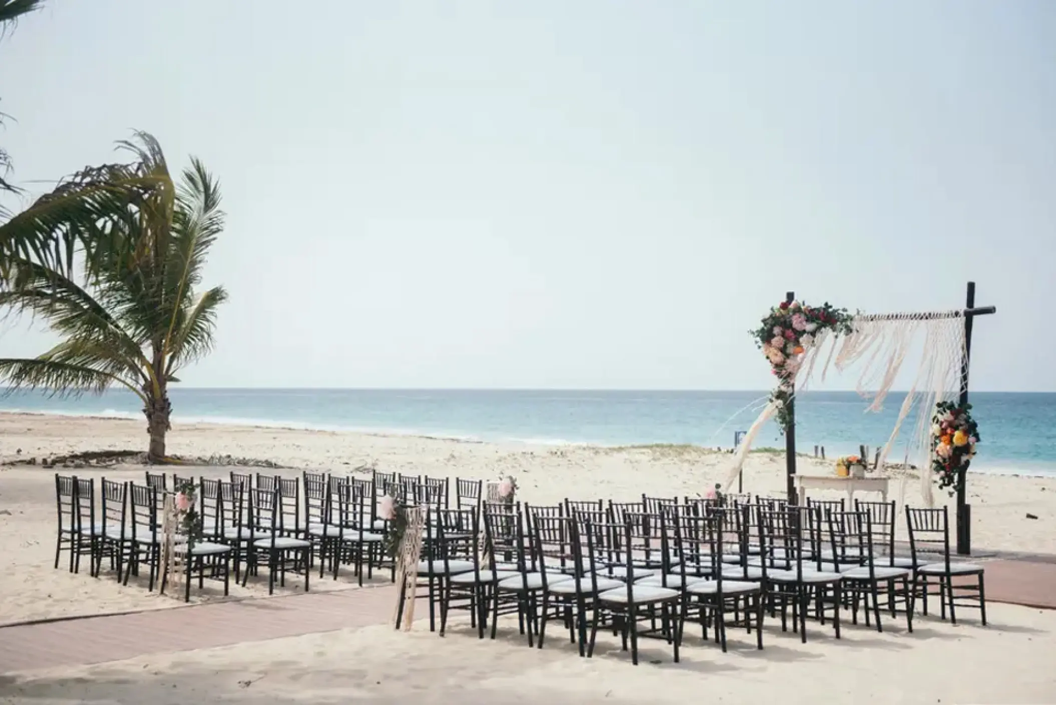 Beachfront wedding ceremony with black chairs and a floral arch at Hard Rock Punta Cana, Punta Cana