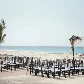 Beachfront wedding ceremony with black chairs and a floral arch at Hard Rock Punta Cana, Punta Cana