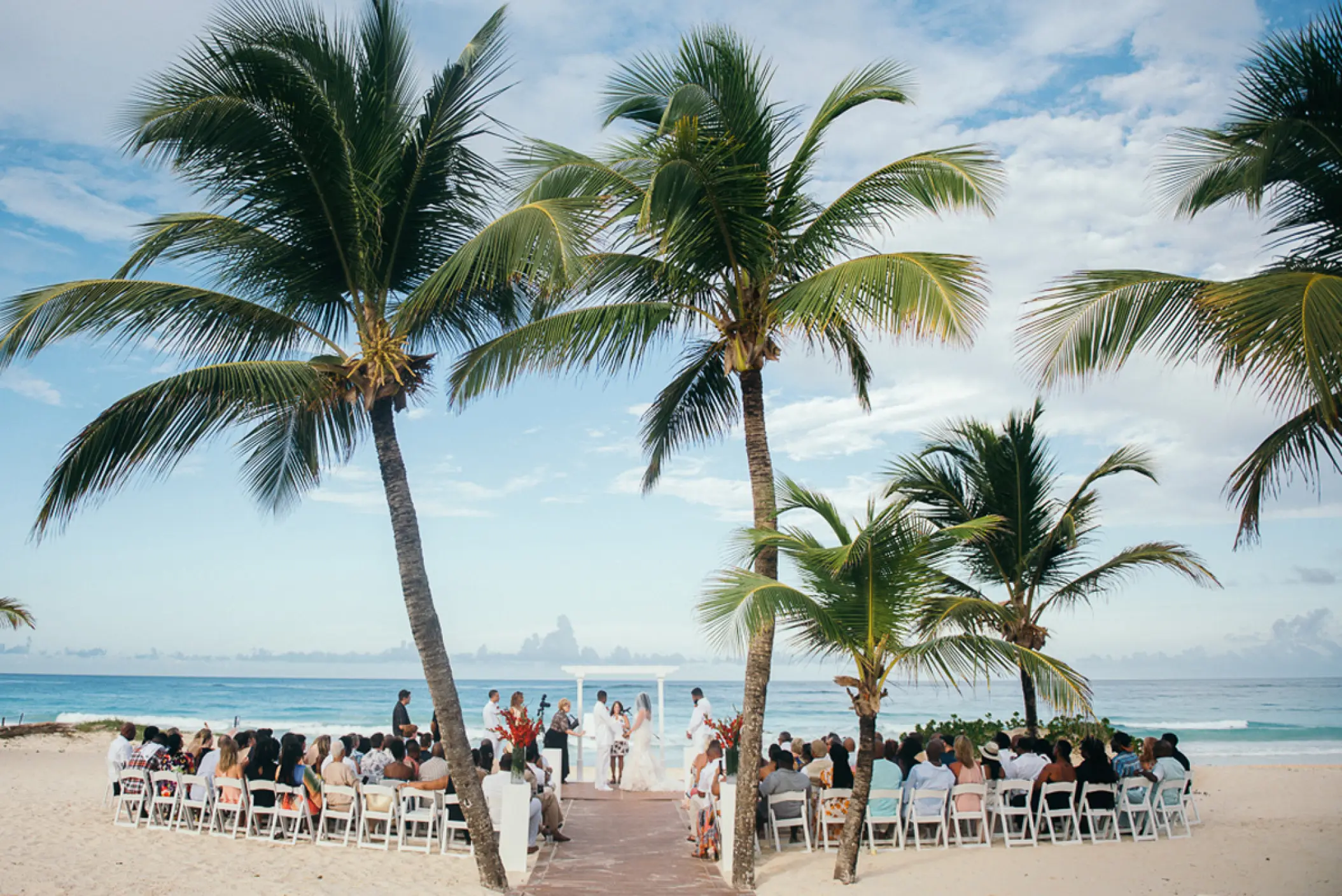 Beachfront wedding ceremony with white chairs and palm trees at Hard Rock Hotel Punta Cana