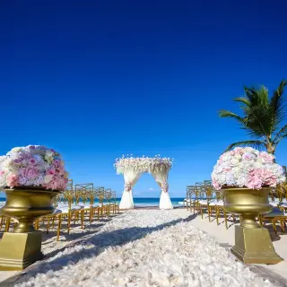 Beachfront wedding ceremony with a floral gazebo and gold chairs at Hard Rock Punta Cana
