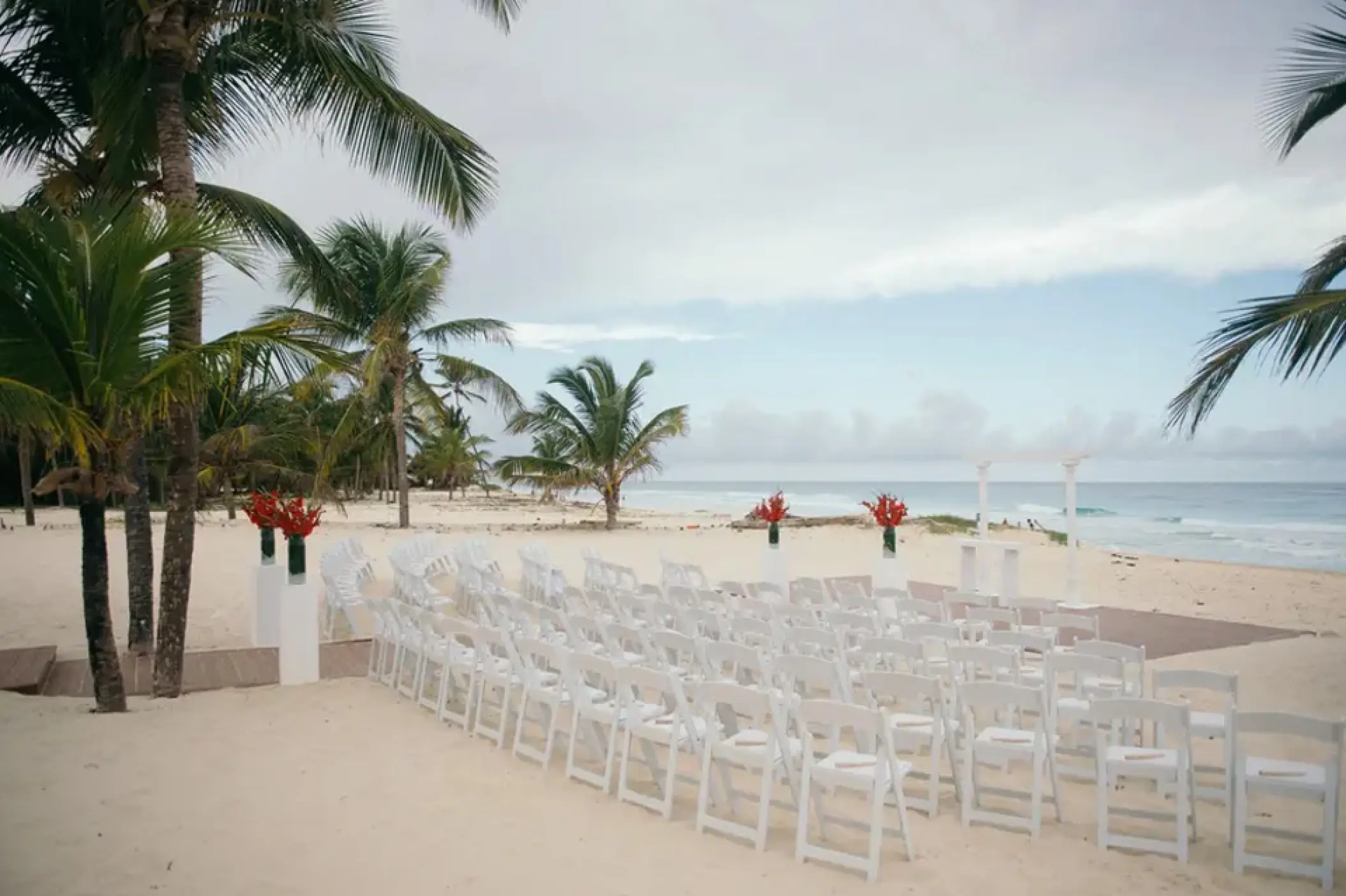 Beachfront wedding ceremony with white chairs and red flowers at Hard Rock Punta Cana