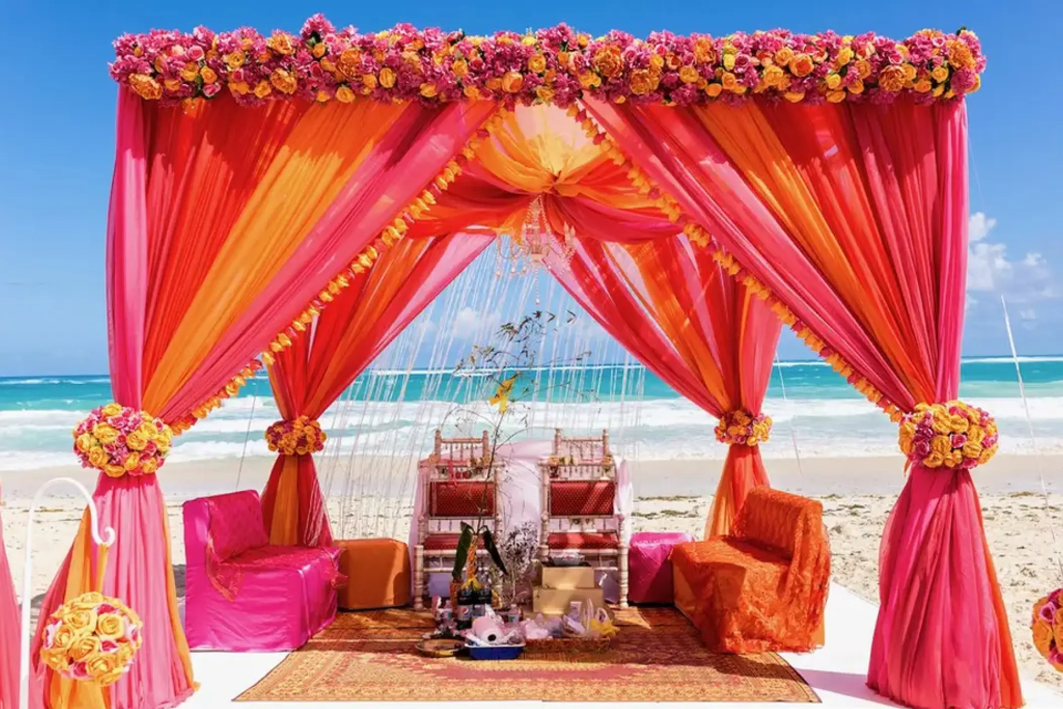 Beachfront Indian wedding ceremony setup under a pink and orange mandap at Hard Rock Punta Cana