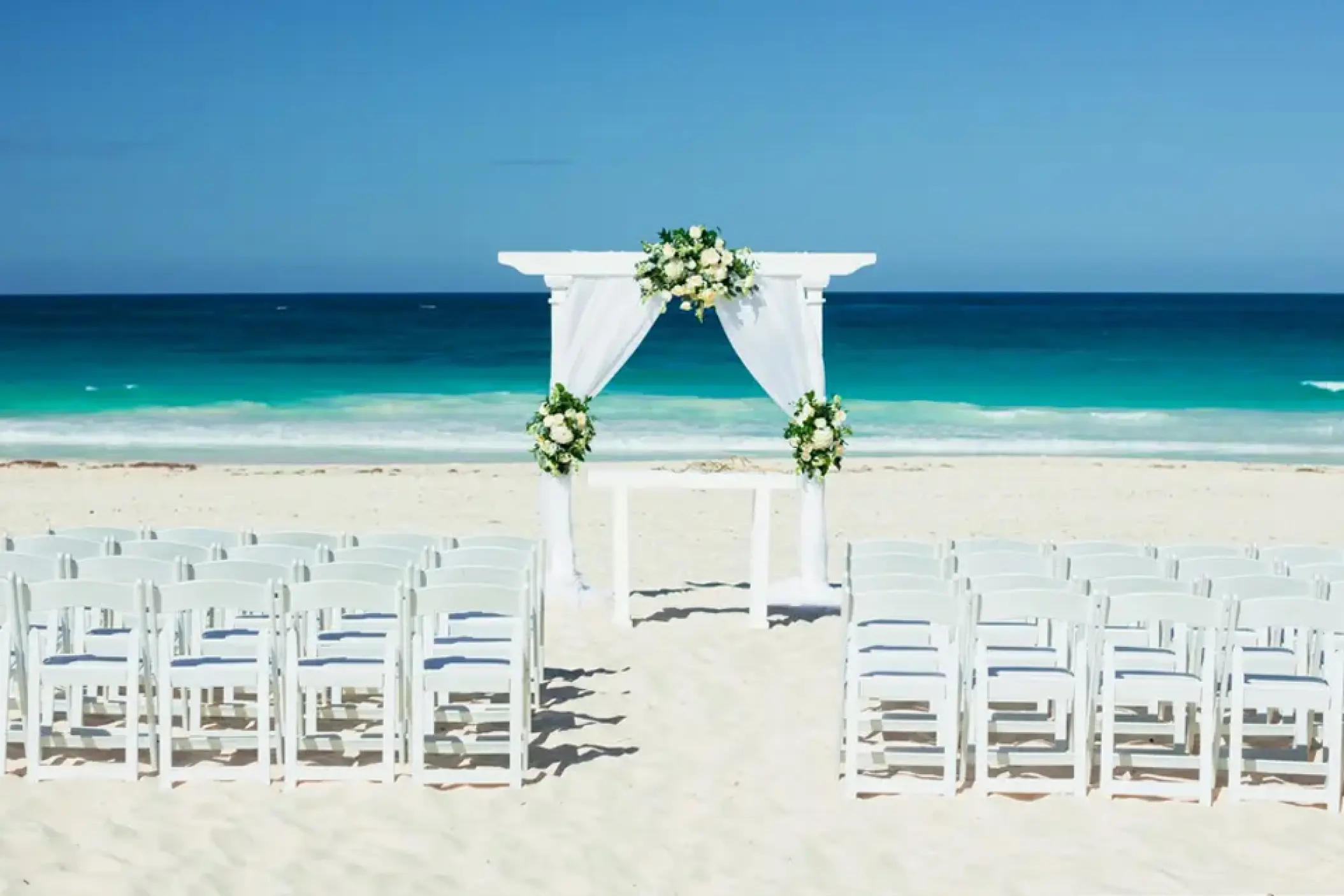 Beachfront wedding ceremony setup with white arbor at Hard Rock Hotel Punta Cana, Punta Cana