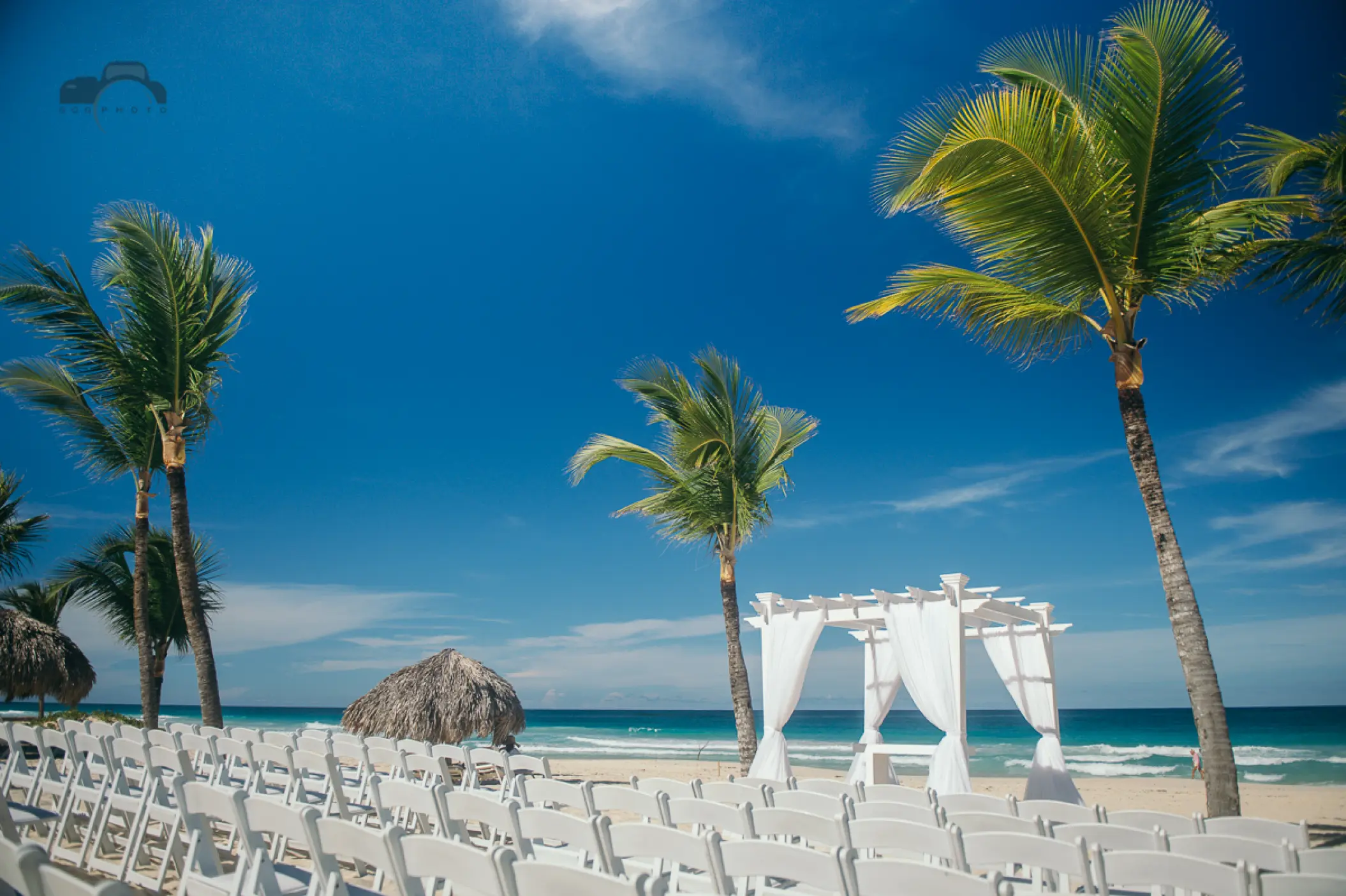 Beachfront wedding ceremony with white huppah and chairs at Hard Rock Punta Cana