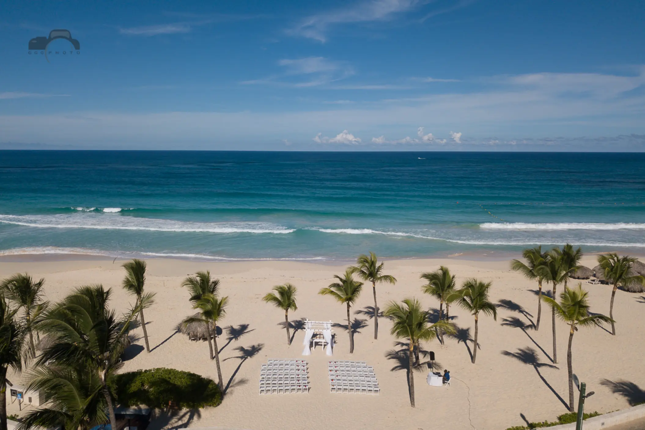 Beachfront wedding ceremony with white chairs and palm trees at Hard Rock Hotel Punta Cana, Punta Cana
