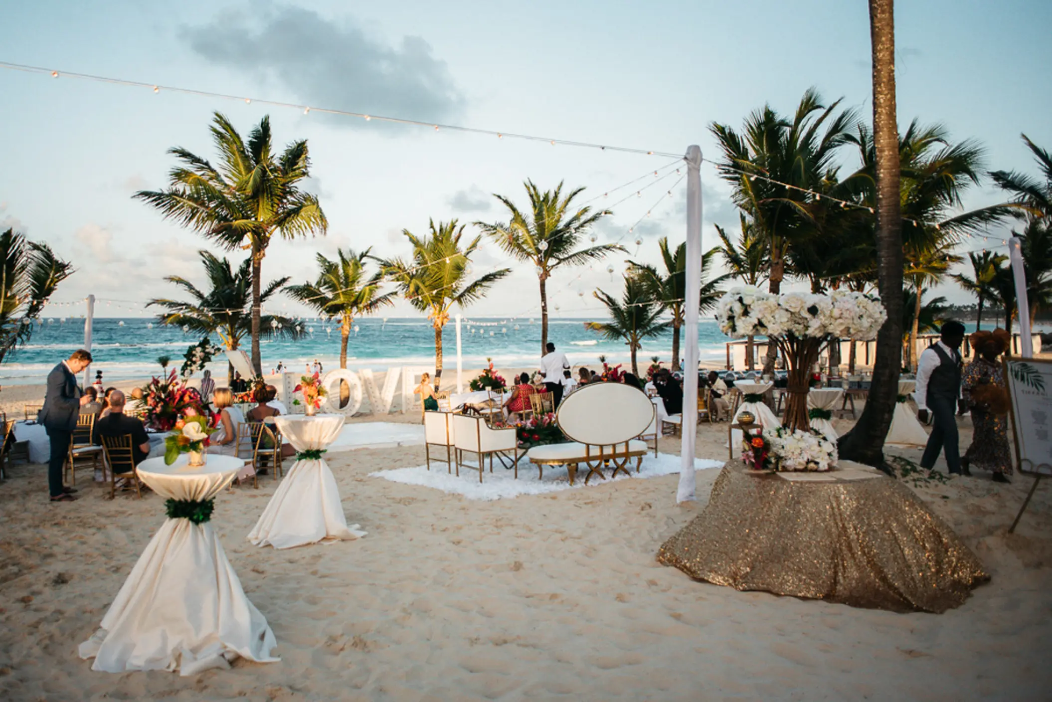Beachfront wedding reception with cocktail tables and palm trees at Hard Rock Punta Cana