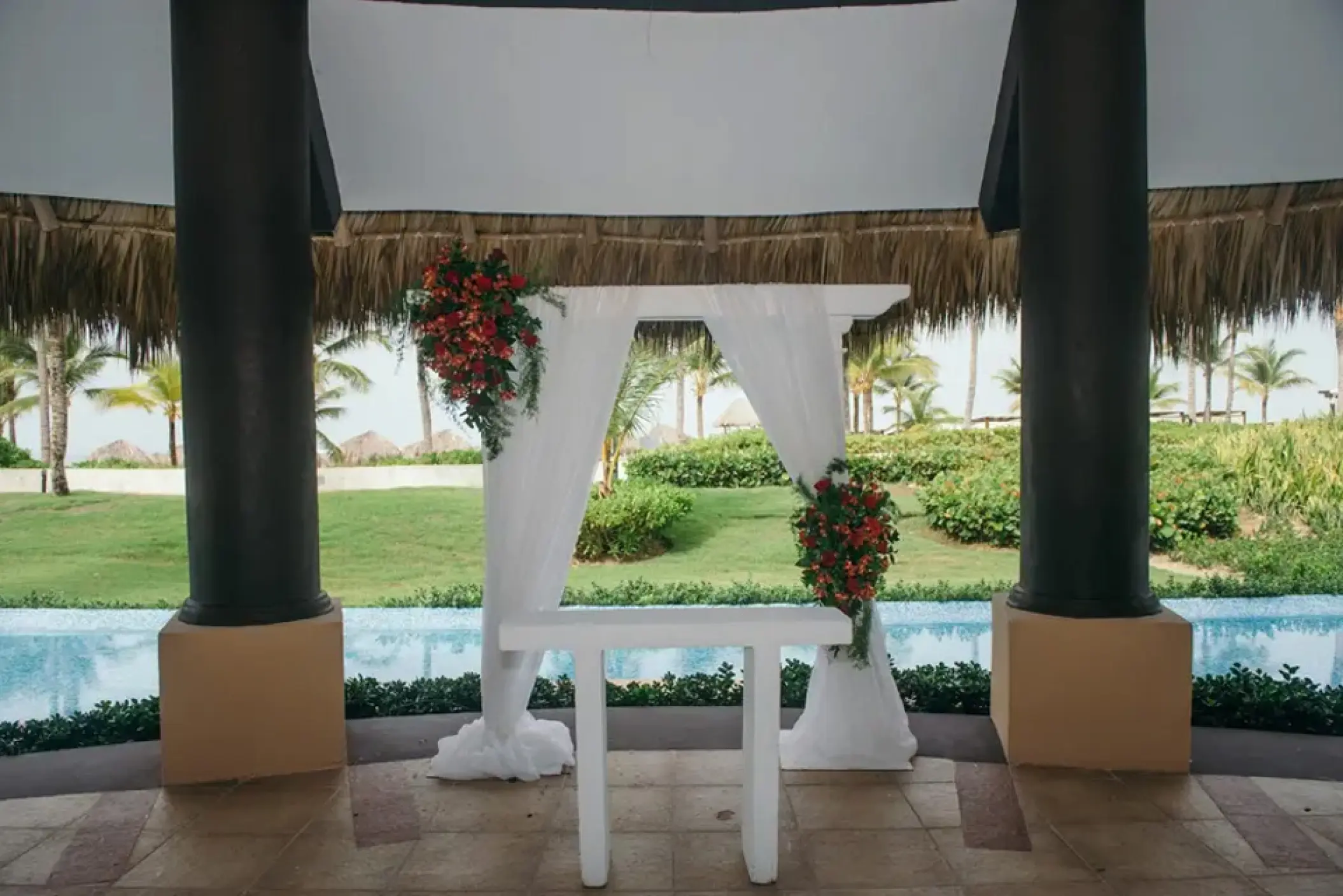 White draped wedding ceremony arch in a thatch-roof gazebo at Hard Rock Punta Cana