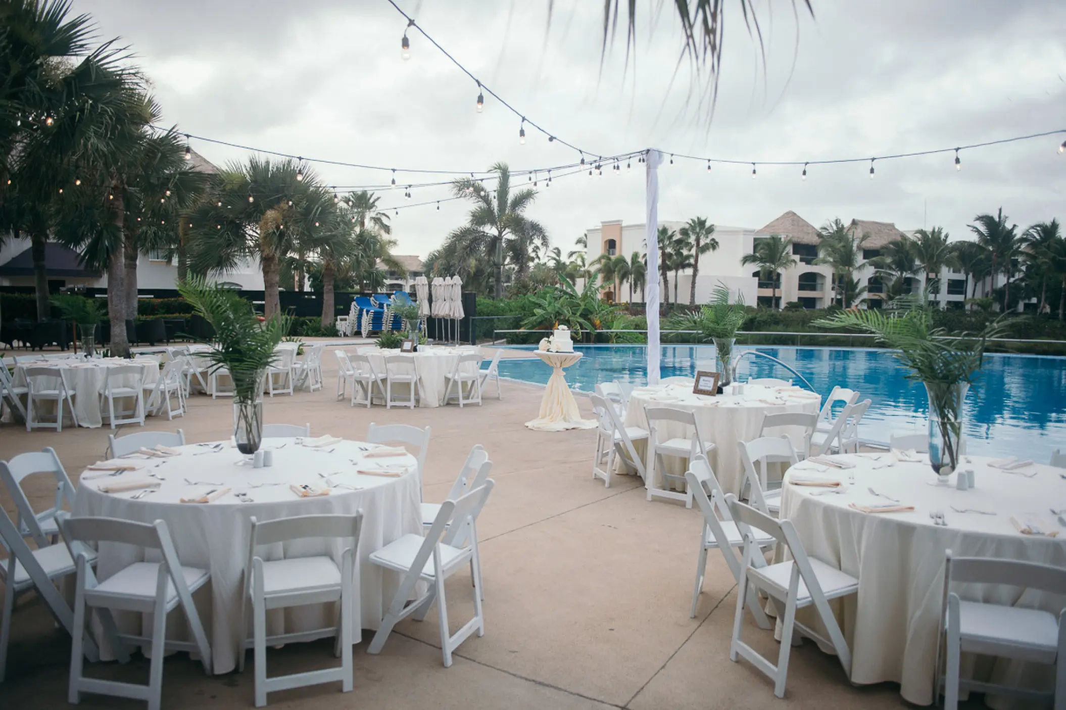 Poolside wedding reception at Hard Rock Punta Cana featuring white tables and string lights, Punta Cana