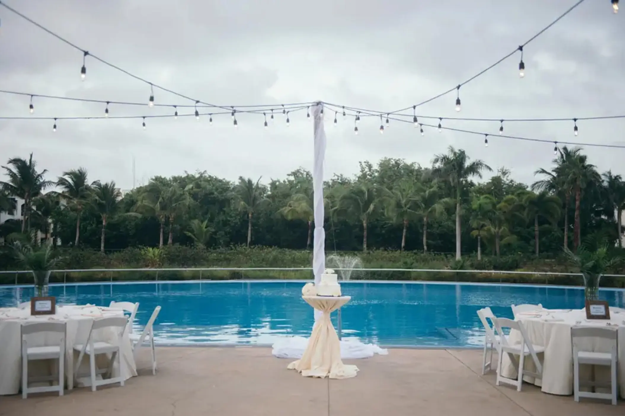 Poolside wedding reception with string lights and white table settings at Hard Rock Punta Cana