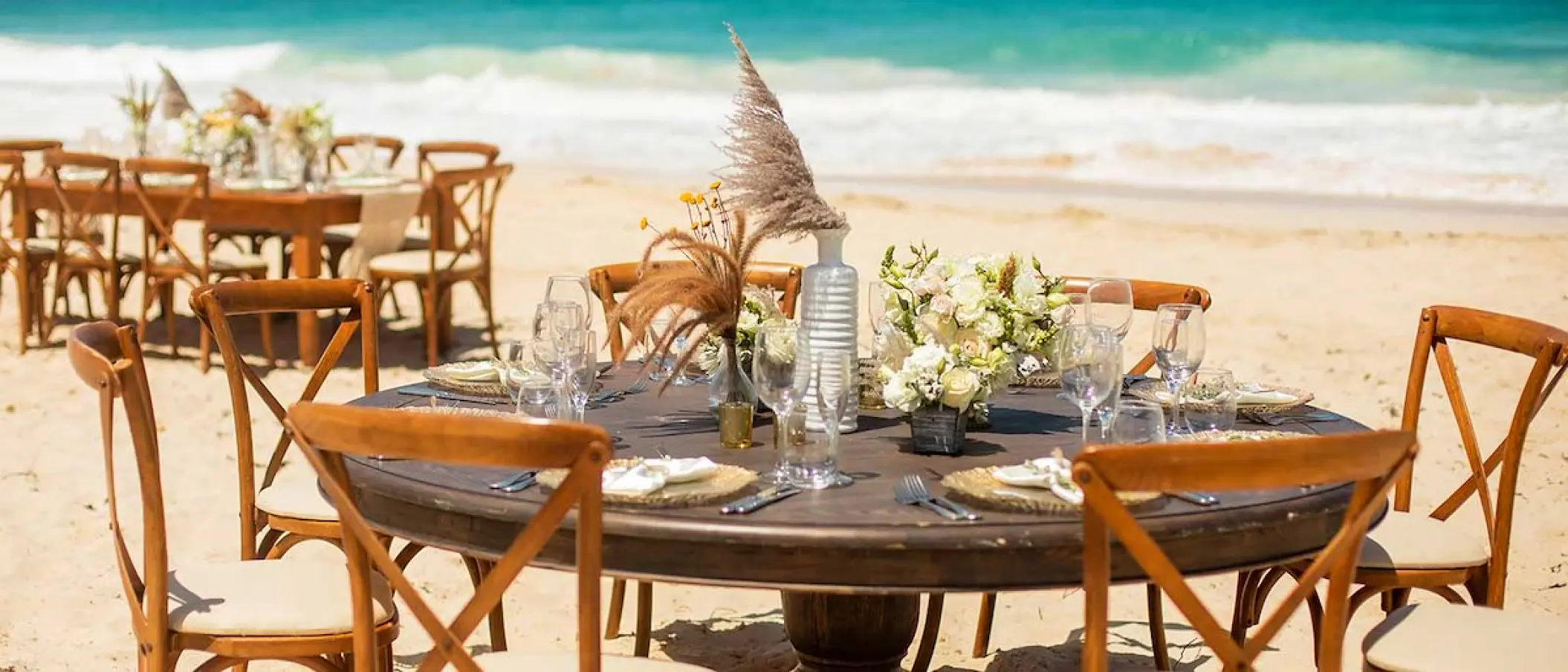 Beachfront wedding reception tables set up on the sand at Hard Rock Cancun