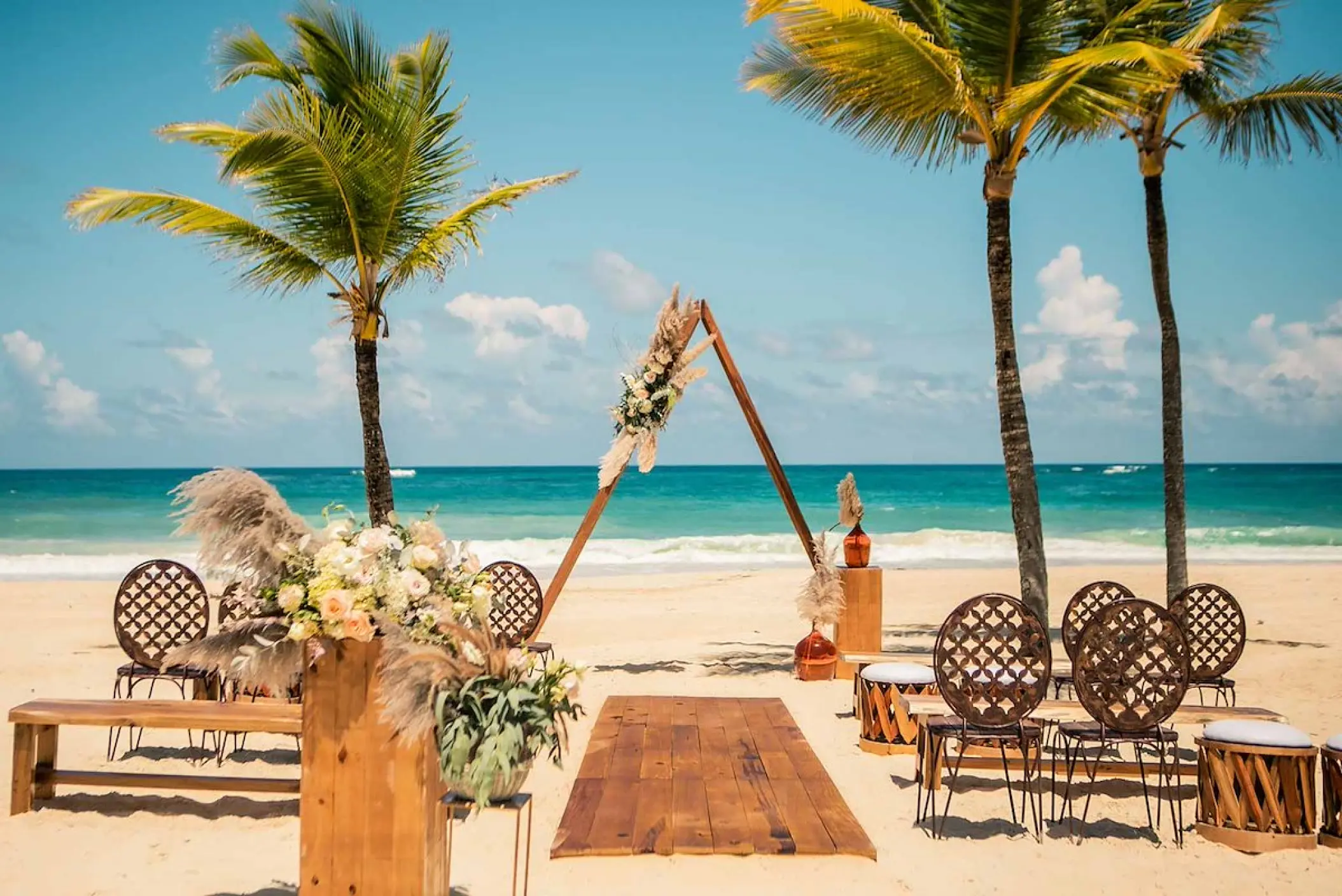 Boho beachfront wedding ceremony with triangular arch at Hard Rock Cancun