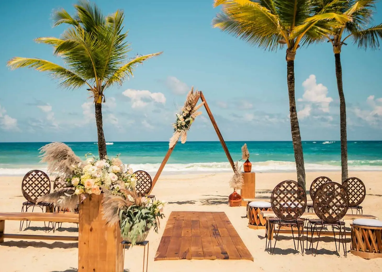 Boho beachfront wedding ceremony with triangular arch at Hard Rock Cancun